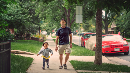 An adult and child walking along a neighborhood street